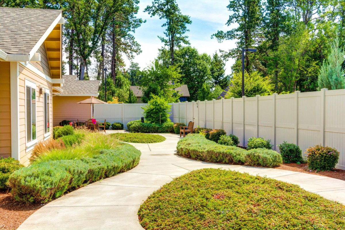 A beautifully landscaped garden with a winding pathway surrounded by lush greenery and trees.