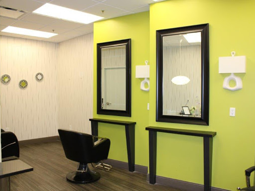 A modern salon interior featuring two mirrors and stylish black chairs against a vibrant green wall.