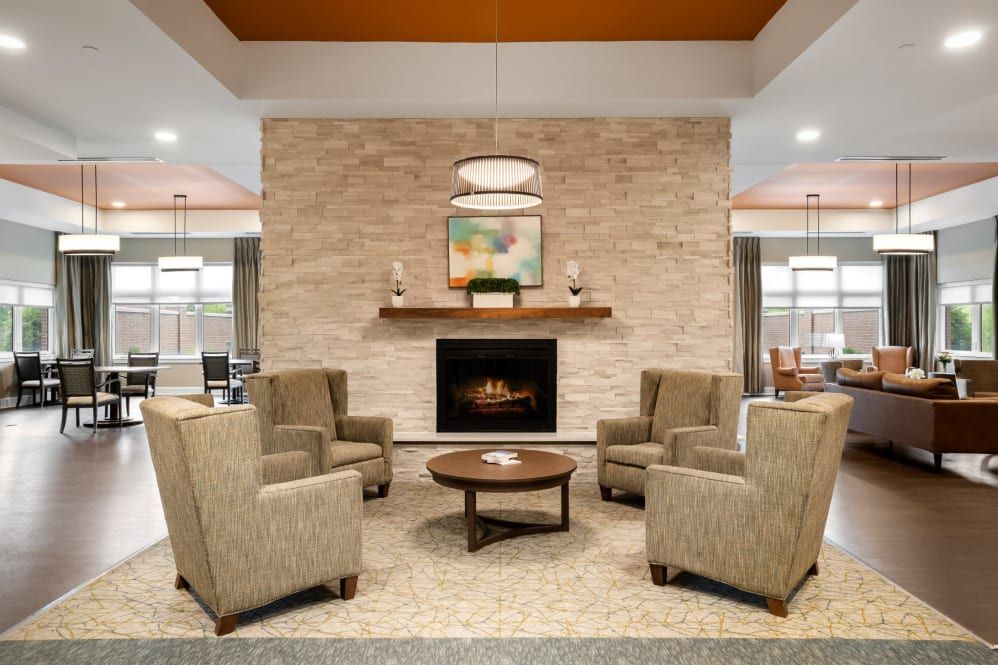 A cozy living room with a modern fireplace, surrounded by four armchairs and a central coffee table.