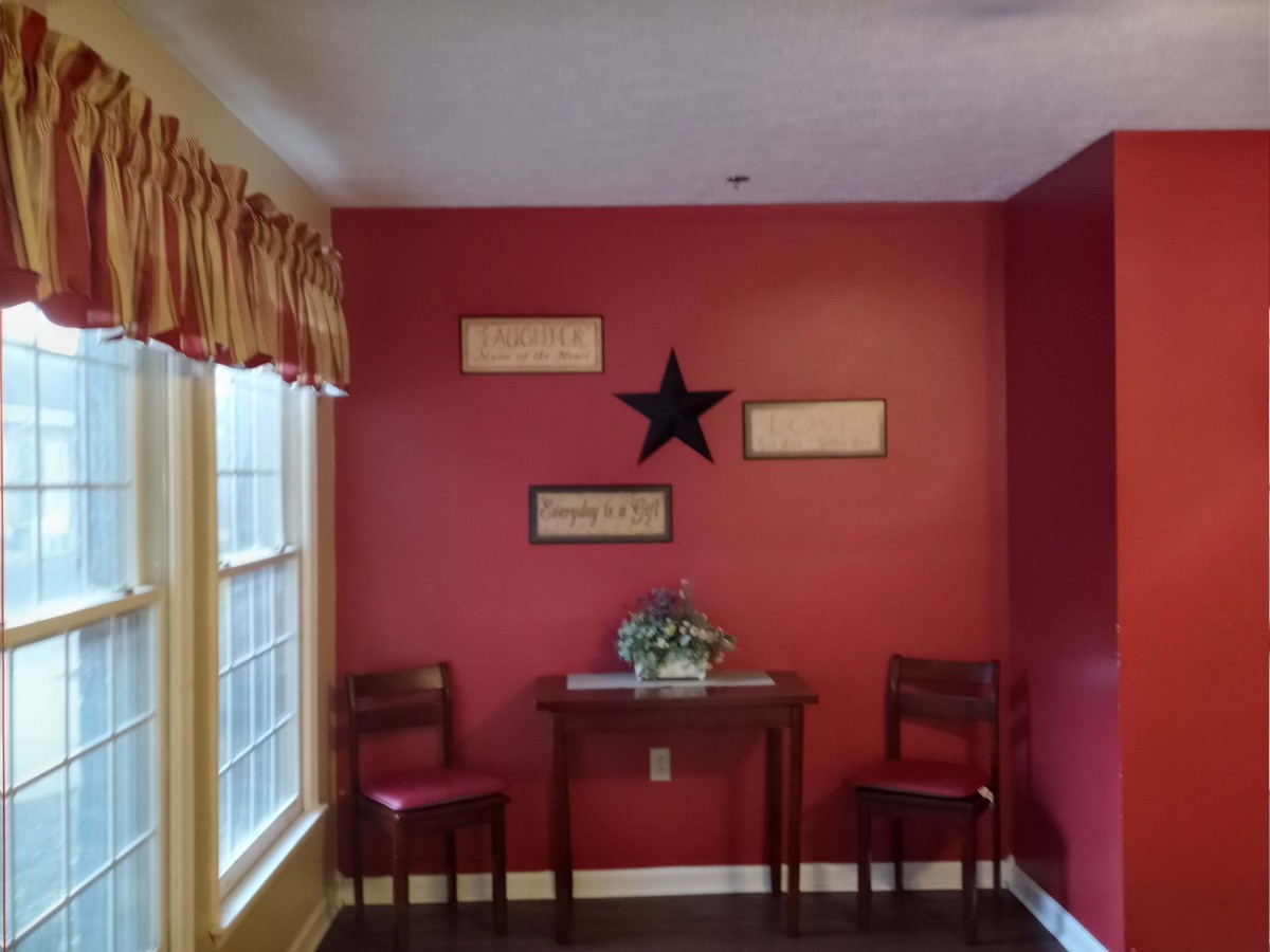 A cozy corner with red walls, featuring two chairs and a small table adorned with decorative items.