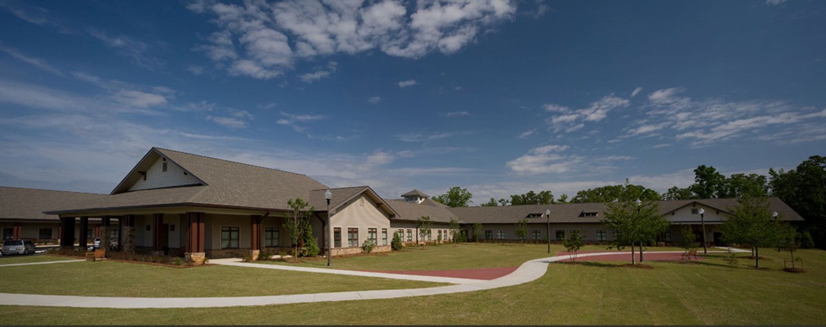 A suburban residential building with a neatly landscaped garden and clear blue sky.