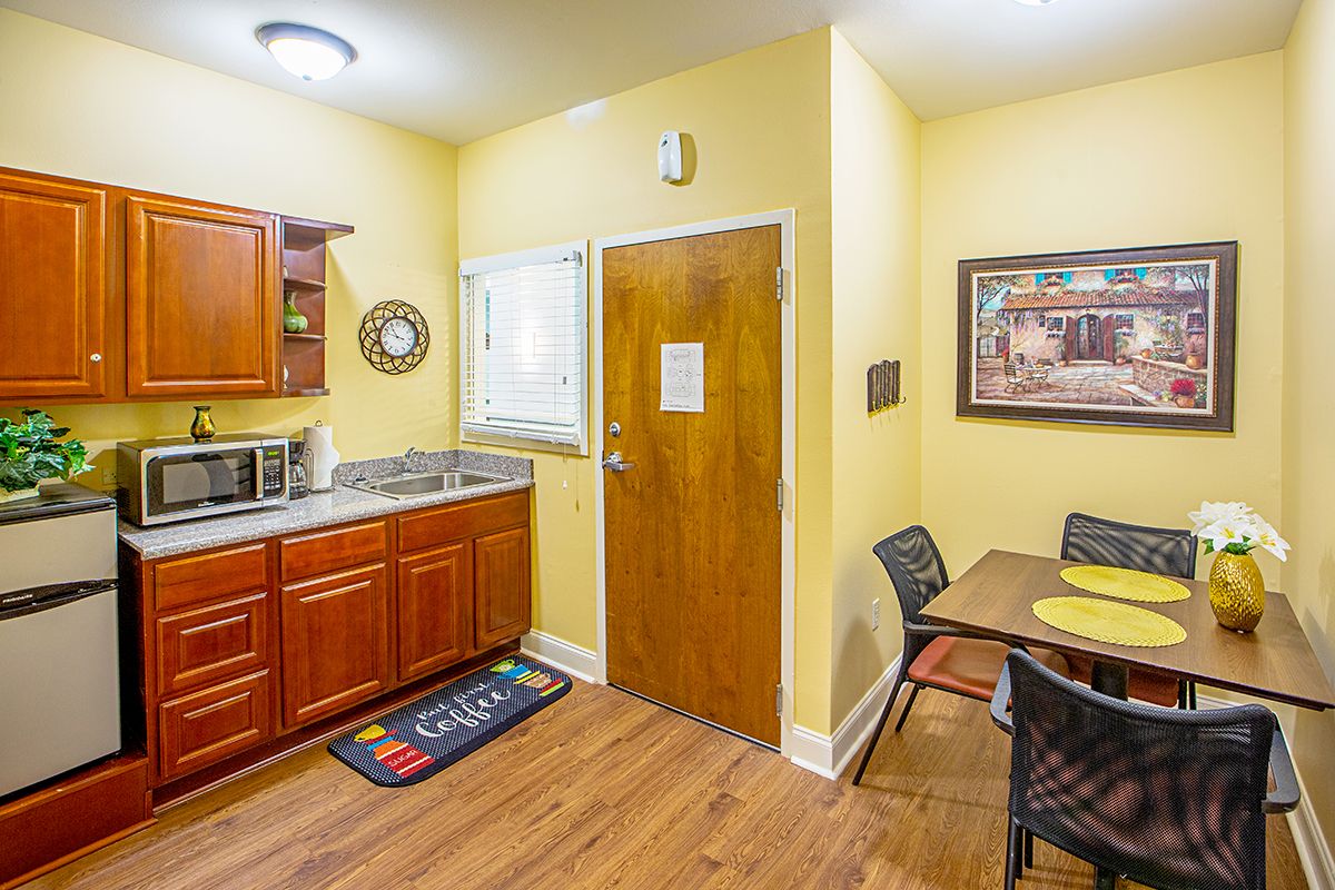A cozy kitchen and dining area with wooden cabinets and a four-seater table.