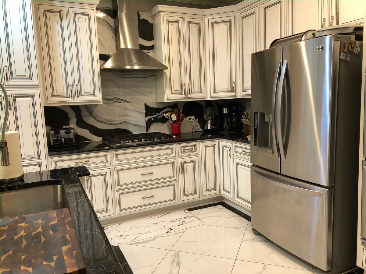 A modern kitchen with stainless steel appliances, elegant cabinetry, and a marble floor.