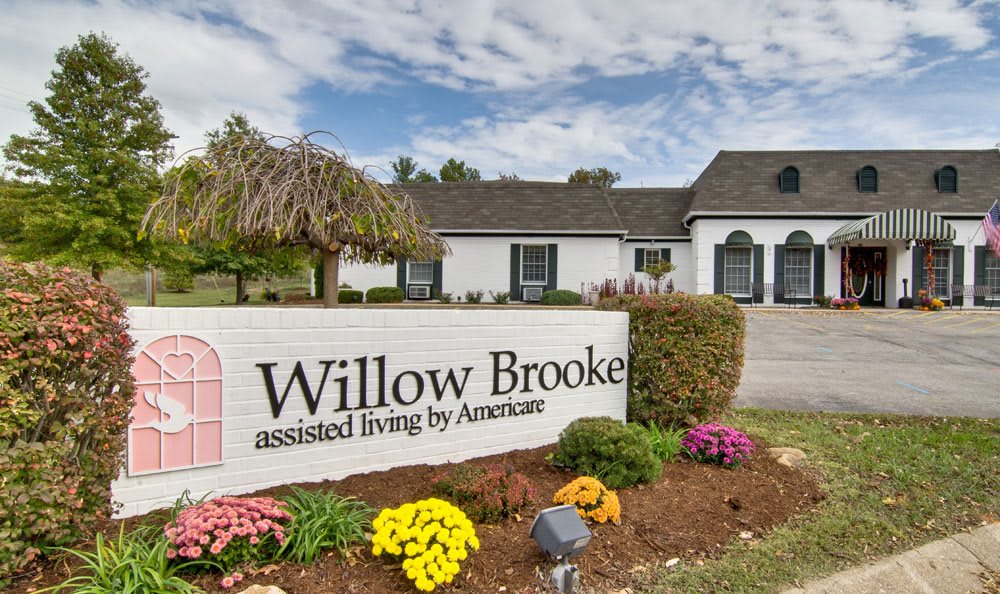 Entrance sign for Willow Brooke assisted living with a view of the building and surrounding landscape.