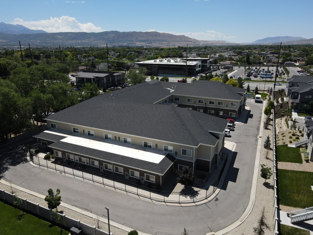 Aerial view of a large building complex with surrounding roads and a parking lot, set against a mountainous backdrop.