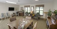 A cozy living room with a puzzle on the table and seating by the windows.