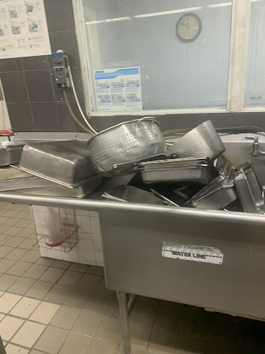 A stack of stainless steel serving trays piled in a commercial kitchen.