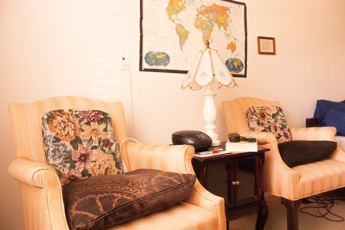 A cozy living room setting with comfortable chairs, a lamp, and a world map on the wall.