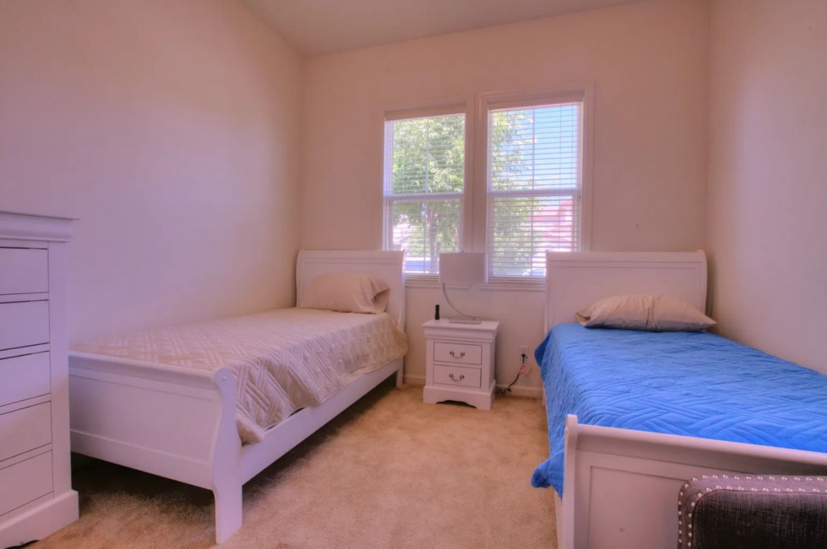 A simple bedroom with two single beds and a small nightstand between them.