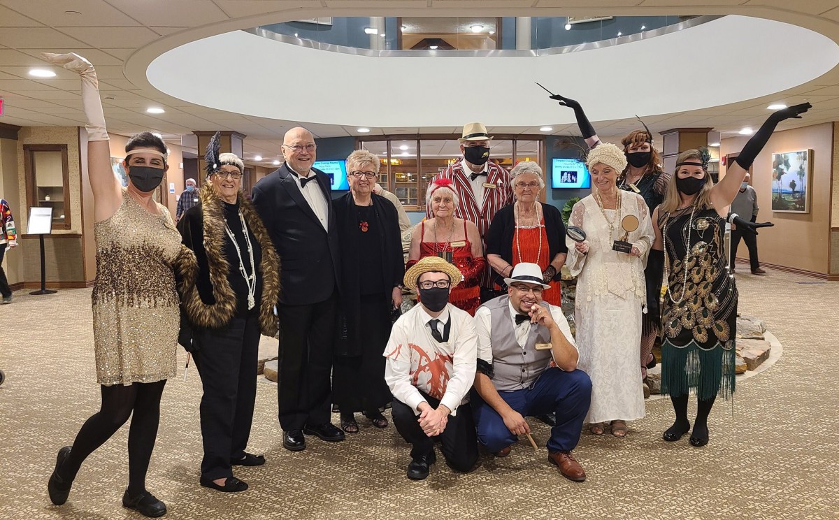 A group of people dressed in various costumes and formal attire at an indoor event.