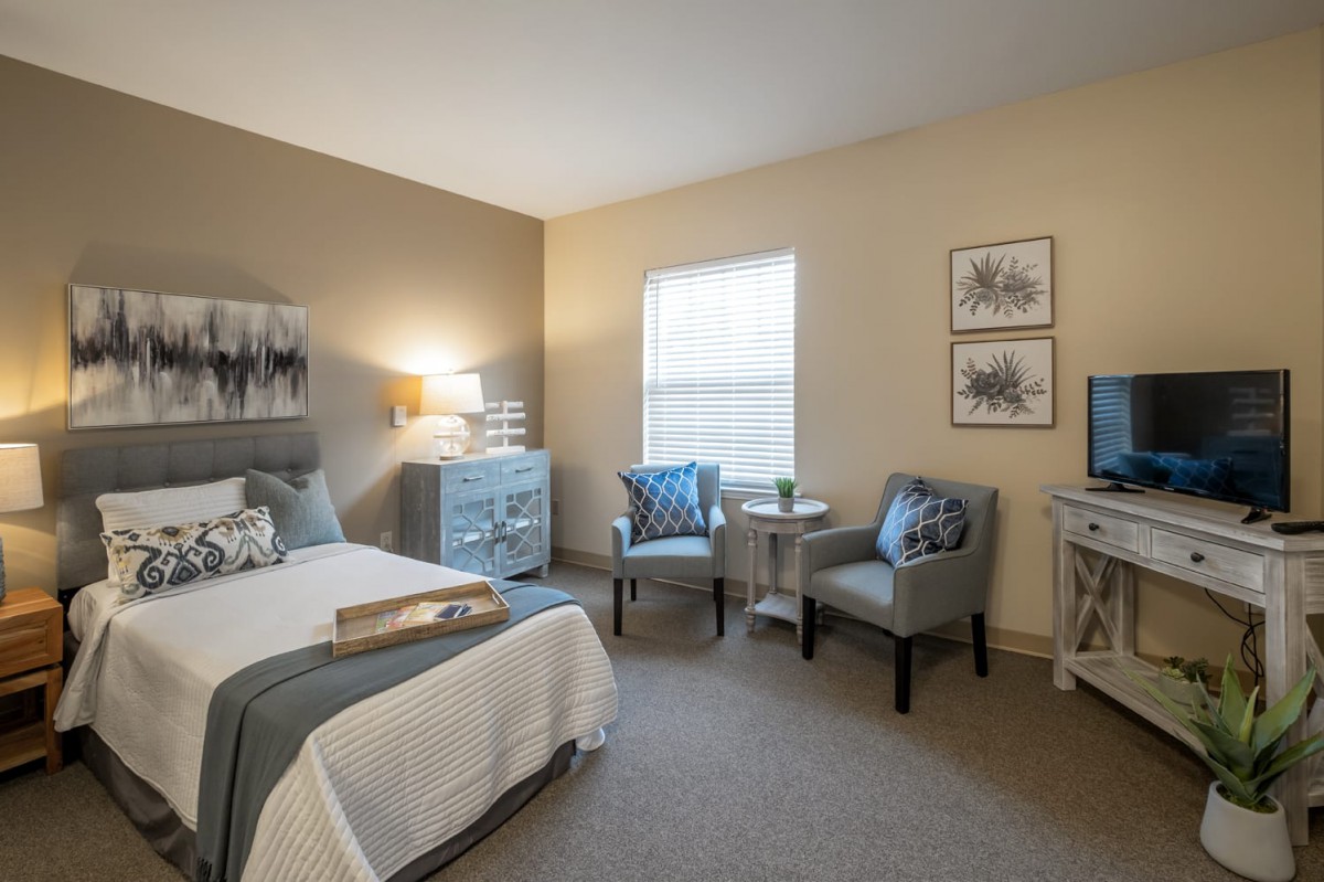 A modern and cozy bedroom with neutral tones, featuring a comfortable bed, chairs, and stylish decor.