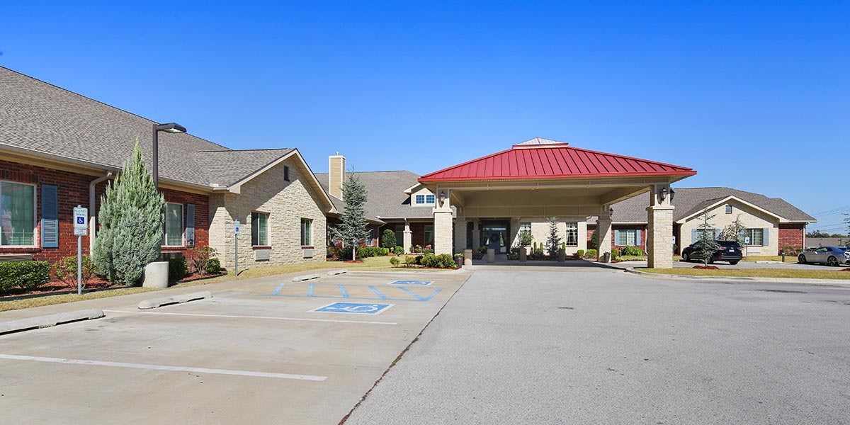 A building with a red roof entrance and an adjacent parking area under a clear blue sky.
