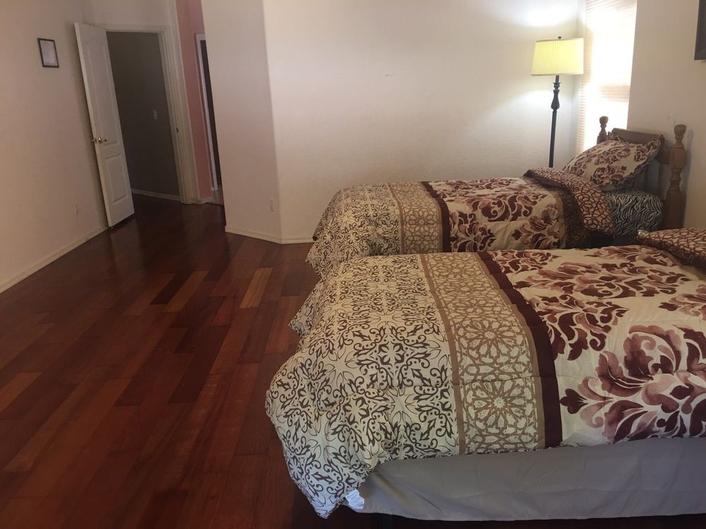 A cozy bedroom with two twin beds and a warm lamp on a hardwood floor.