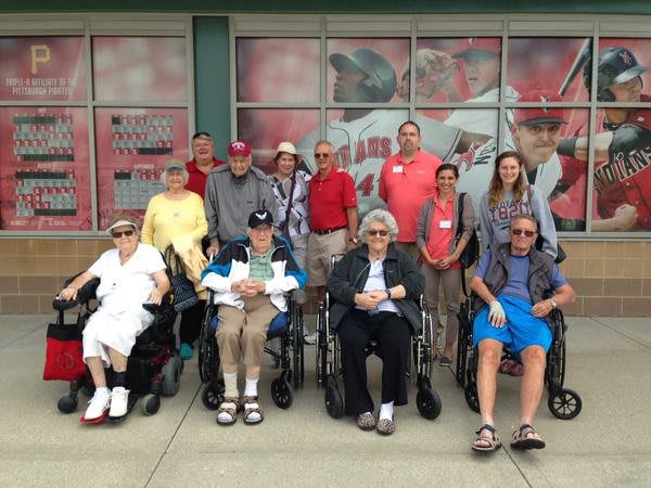 A group of elderly people, some in wheelchairs, posing for a photo outside.