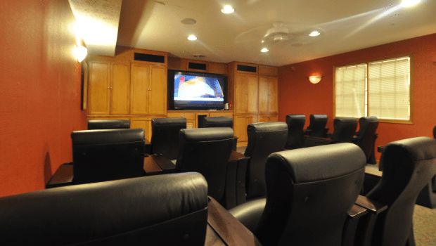 A conference room with leather chairs facing a television mounted on a wooden paneled wall.