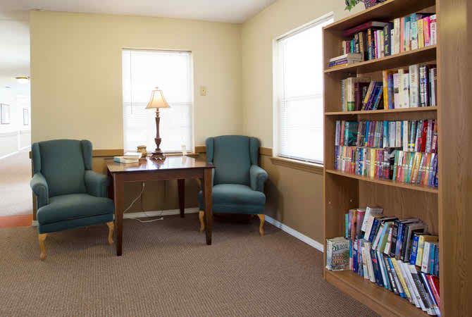 A cozy reading corner with two chairs, a table, and bookshelves.