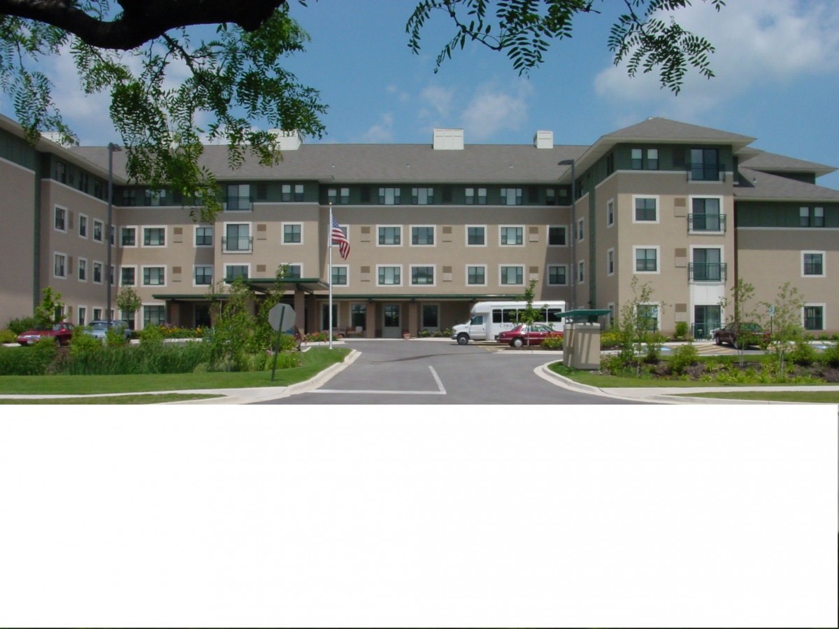 A modern hotel building with a parking area and landscaped surroundings.