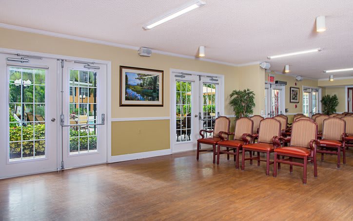 A neatly arranged waiting room with chairs, a painting on the wall, and glass doors leading outside.