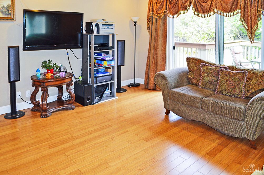 A cozy living room with a television and sound system, featuring a comfortable sofa and wooden flooring.