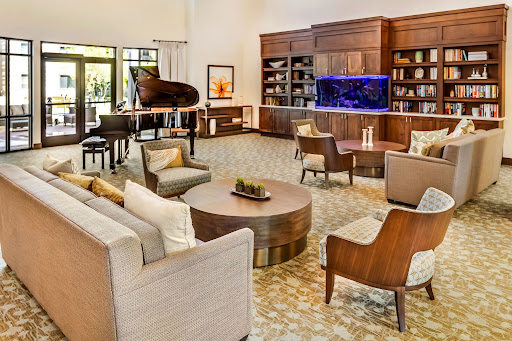 A stylish and inviting lounge area featuring comfortable seating, a piano, and an aquarium.