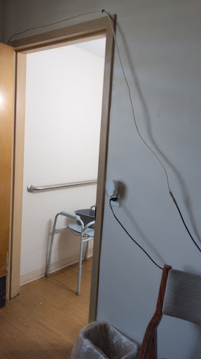 A view of a room with a door, a walker in the corner, and some cables along the wall.
