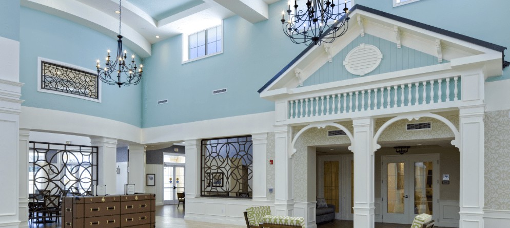 A spacious and elegantly designed interior with a high ceiling, featuring a chandelier and decorative elements.