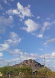 A scenic view of a mountain under a blue sky with scattered clouds.