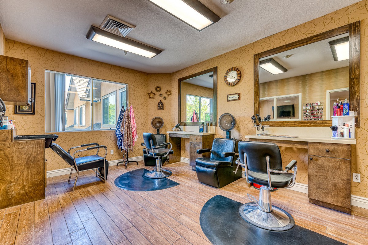 A well-lit hair salon interior featuring multiple styling chairs, mirrors, and a wooden floor.