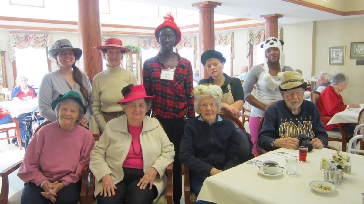 A group of people wearing hats, gathered indoors for a social event.