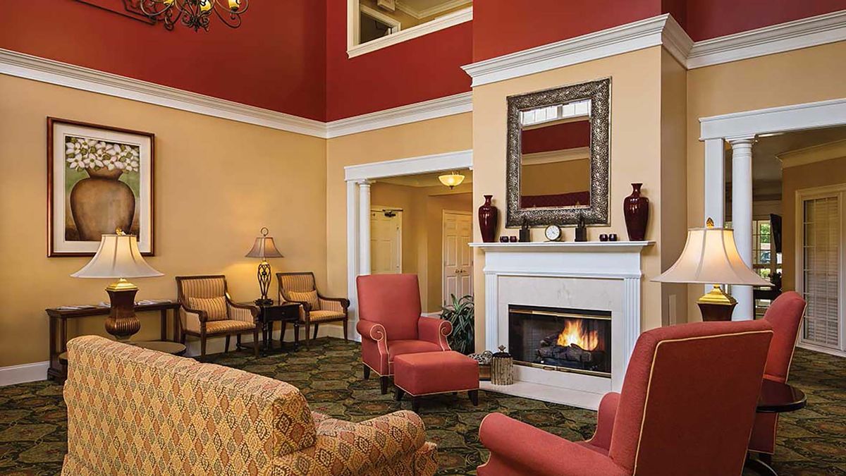 A cozy living room with red and beige walls, featuring a fireplace, armchairs, and elegant decor.