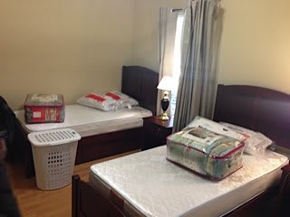 A bedroom with twin beds, mattresses, and a lamp by the window.