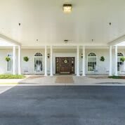 A covered building entrance with columns and large wooden doors.