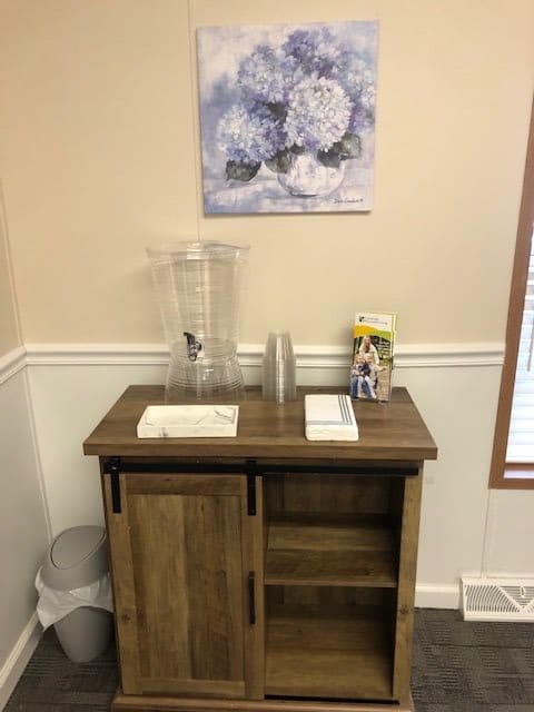 A small cabinet with a water dispenser and cups in a decorated room.