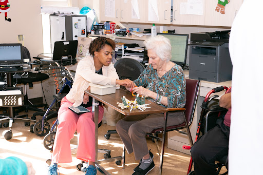 A caregiver engages with an elderly woman, fostering connection and support through shared activities.