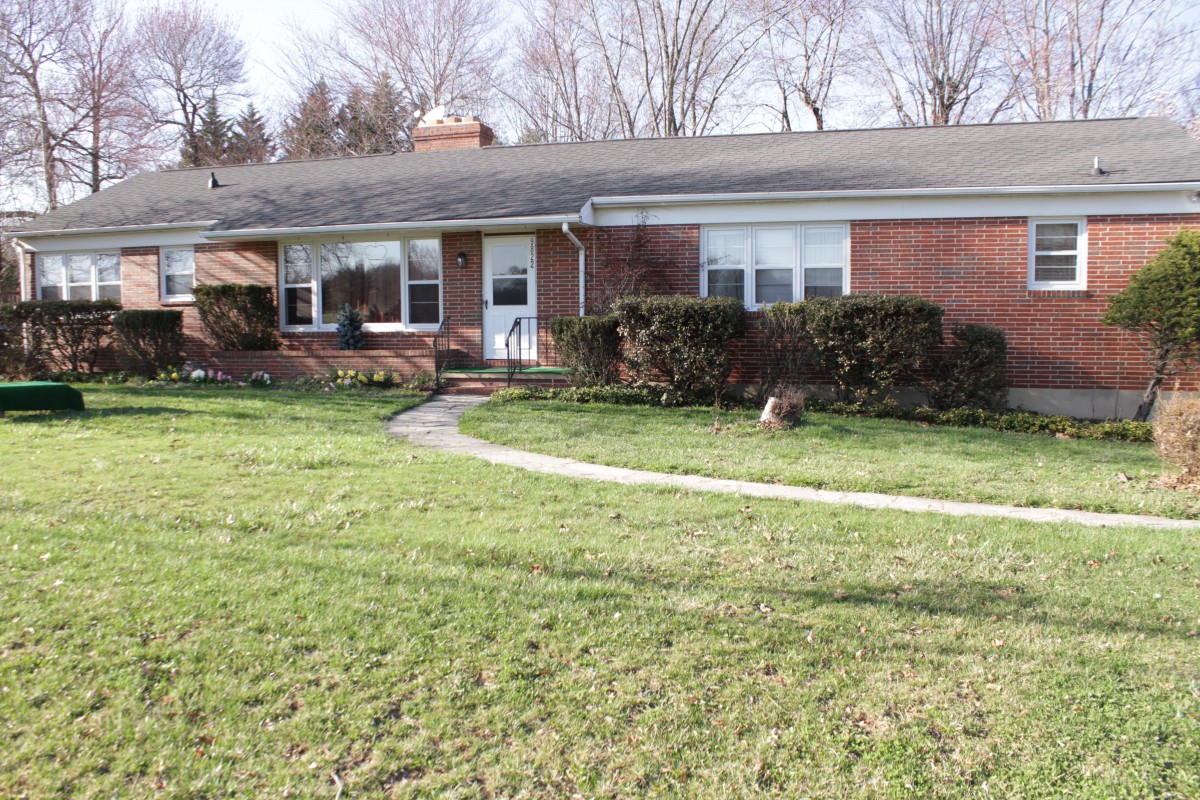 A single-story ranch-style brick house with a well-maintained front yard and lawn.