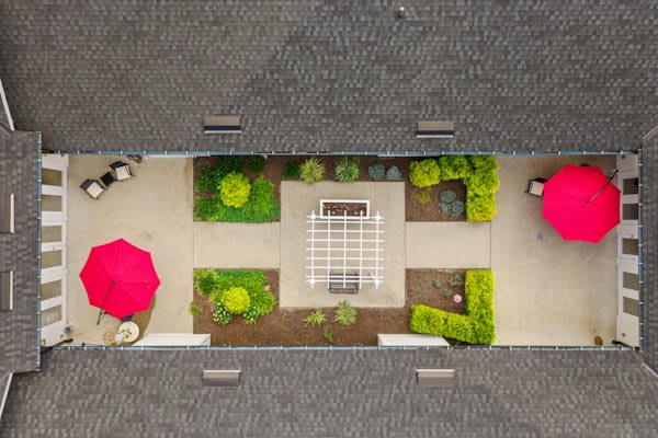 Aerial view of a landscaped courtyard with a patio and red umbrellas.
