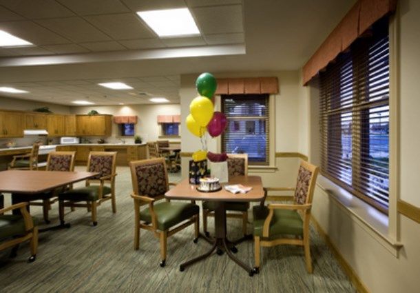 A cozy dining area with tables and chairs, decorated with colorful balloons.