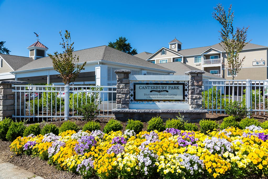 A well-maintained apartment complex with vibrant flowers and clear signage.