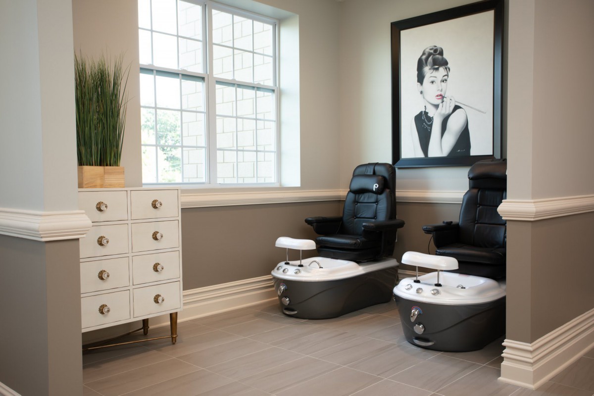 A modern spa interior featuring two pedicure chairs, a large window, and stylish decor.