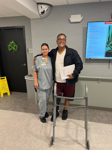 A patient standing with a nurse, showcasing the support and care during rehabilitation.