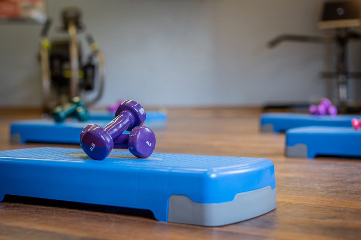 A gym setting featuring a purple dumbbell on a blue step platform.