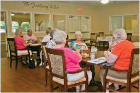 A group of seniors enjoying a meal and conversation in a dining area.