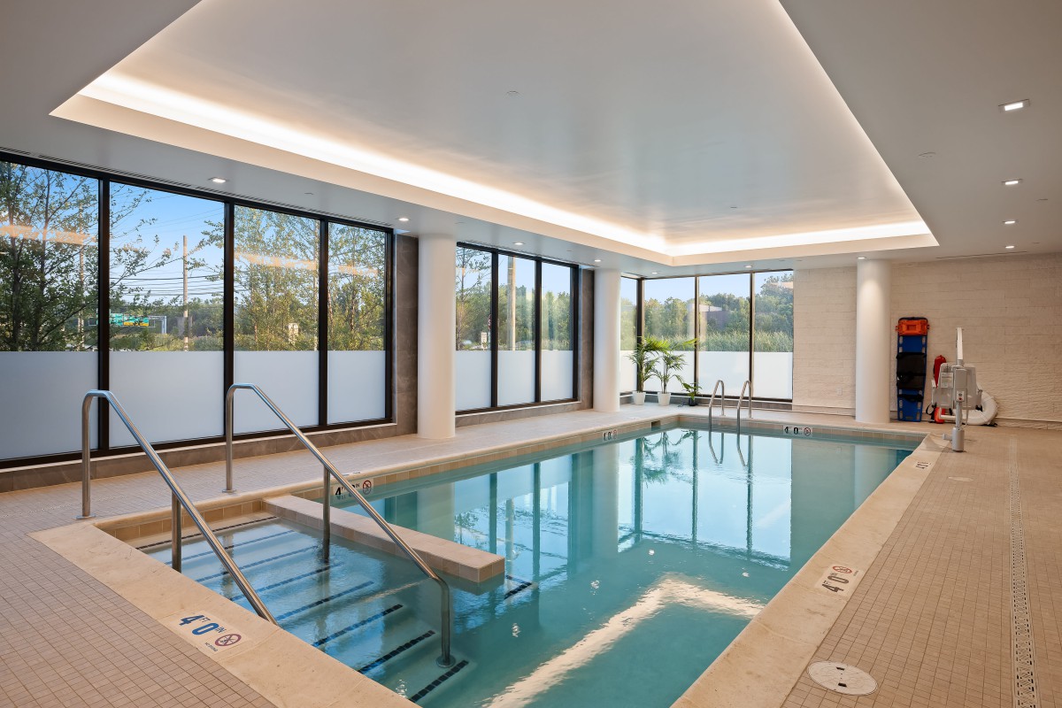 A modern indoor swimming pool with large windows and elegant lighting.