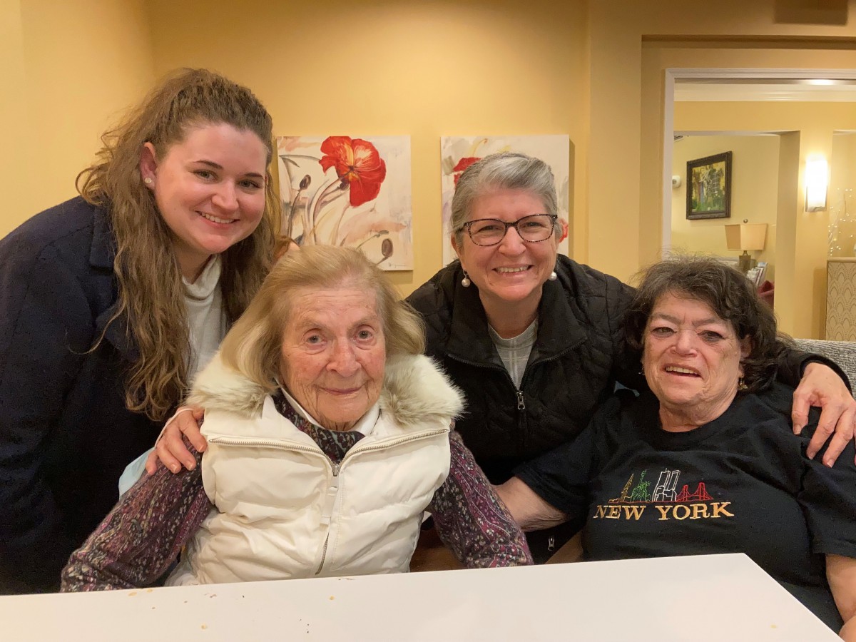A group of women smiling indoors, gathered around a table.