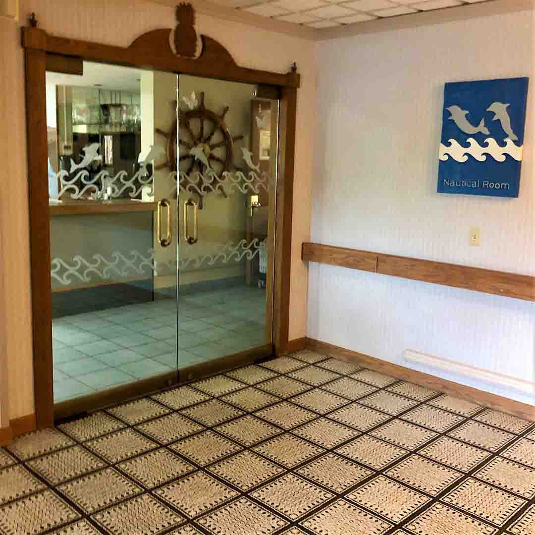 A nautical-themed interior with a large mirror framed by a ship's wheel and visible floor tiles.