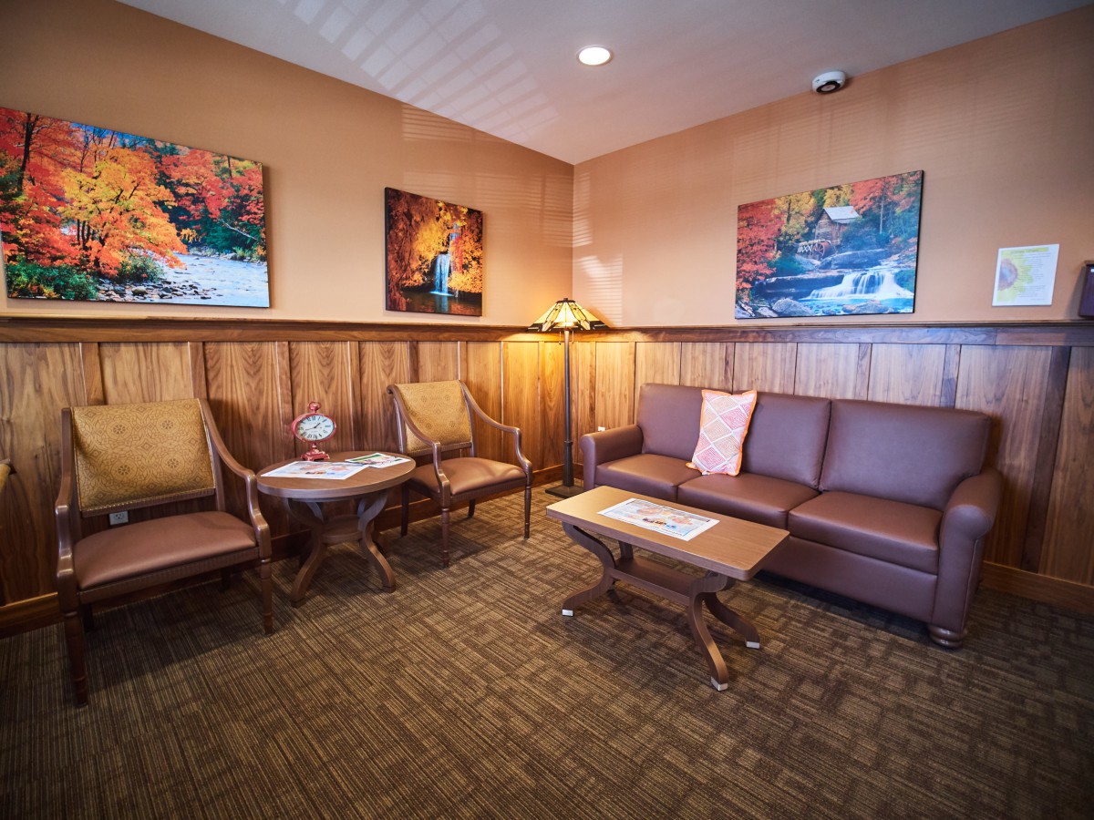 A cozy waiting room with a sofa, chairs, and artwork on the walls.