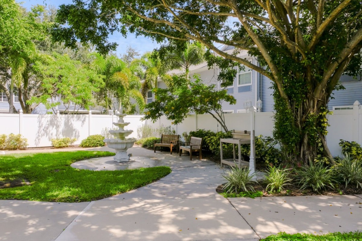 A beautifully landscaped garden with a pathway, fountain, and outdoor seating.