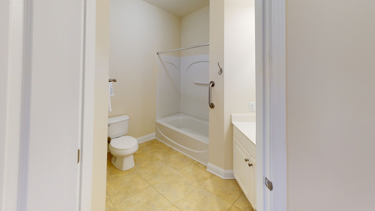 A clean bathroom featuring a bathtub with a shower, toilet, and sink with a tile floor.