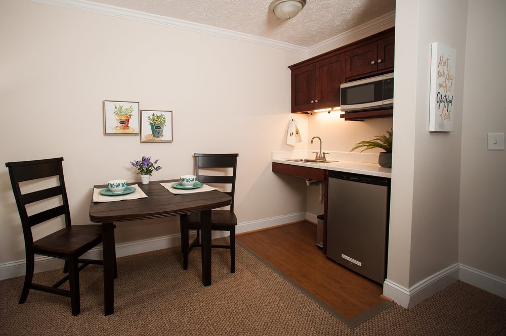 A compact kitchenette with a small dining area, featuring a table set for two.