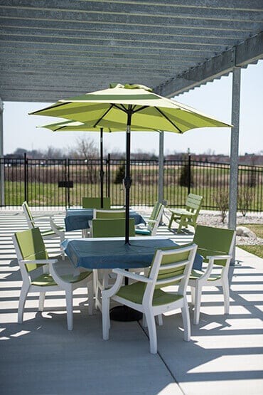 Outdoor patio set with table, chairs, and a green umbrella on a sunny day.